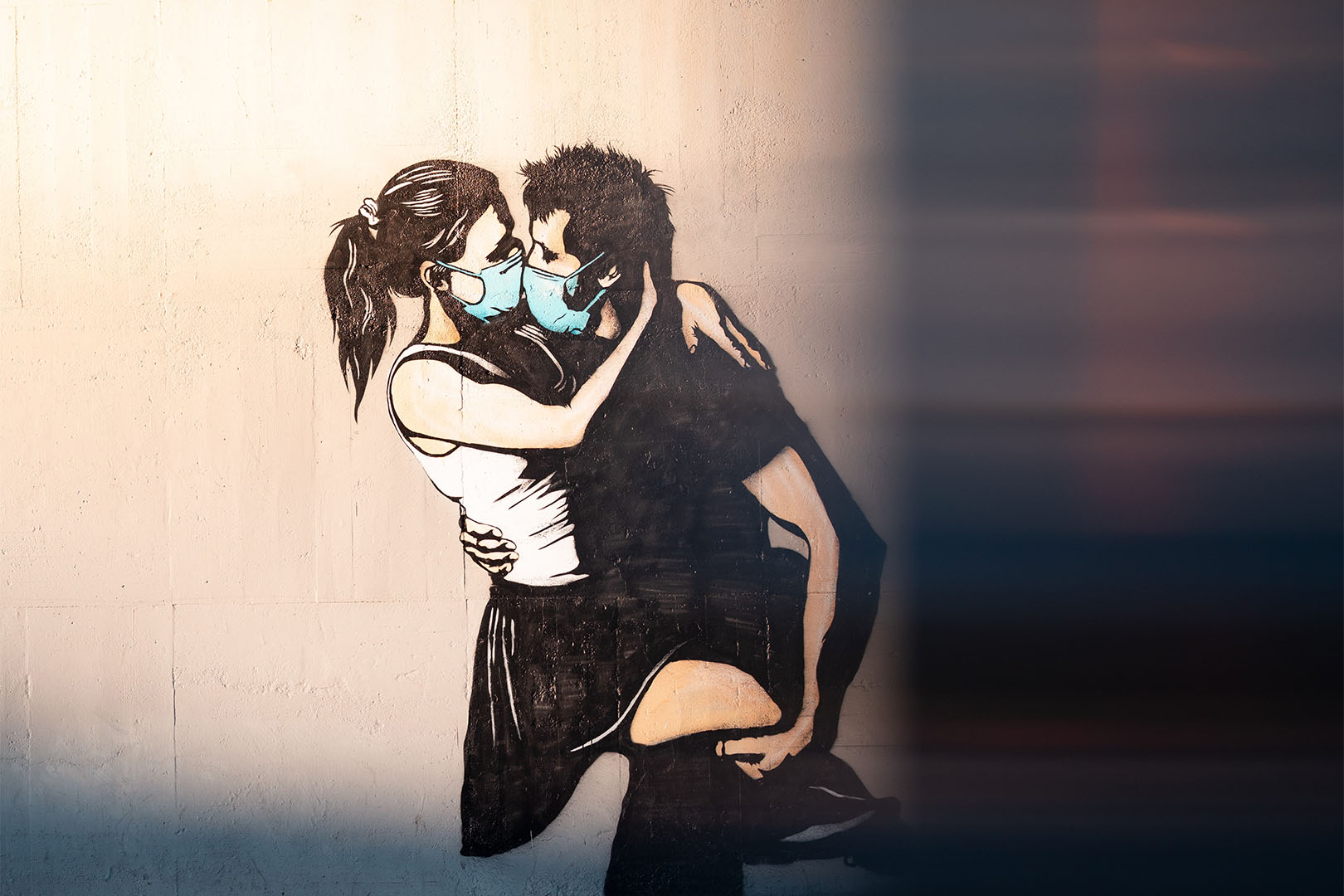 man and woman kissing each other with a face mask on.