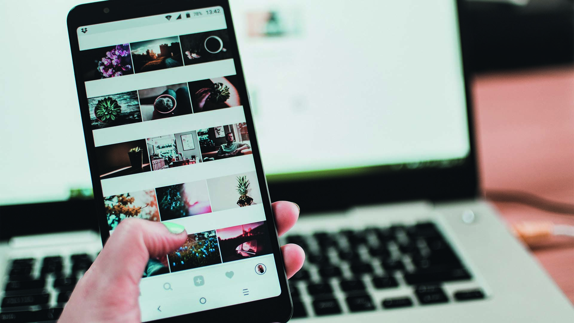 A hand holding a cellphone with photos.